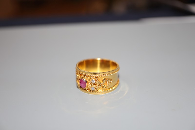 A modern yellow metal, cabochon ruby and diamond set band, with ropetwist decoration, size P, gross 6.1 grams.